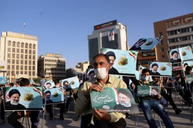 A supporter of  Ebrahim Raeesi holds a poster of him during an election rally in Tehran, June 14, 2021.